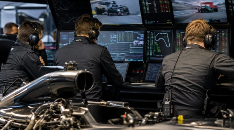 Ingénieurs de Formule 1 analysant les données moteur 2026 dans un garage high-tech pendant la saison F1 2026, illustration du système ADUO mis en place par la FIA.
